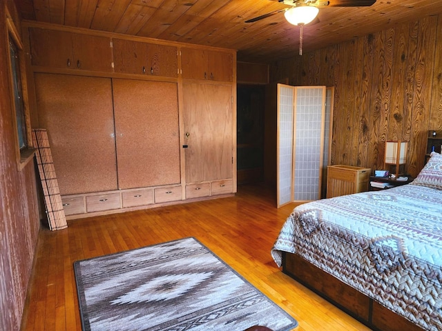 bedroom featuring wood walls, wood ceiling, light wood-type flooring, a closet, and ceiling fan