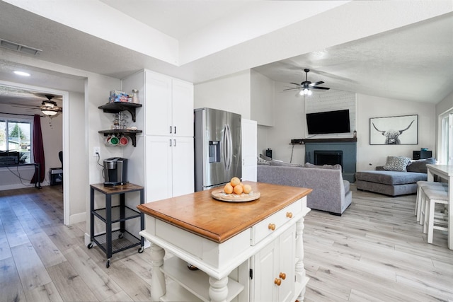 kitchen with stainless steel refrigerator with ice dispenser, lofted ceiling, light hardwood / wood-style flooring, and white cabinets