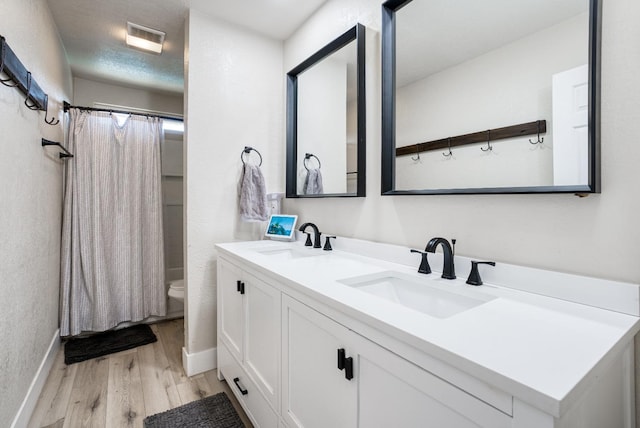 bathroom with wood-type flooring, vanity, a textured ceiling, and toilet