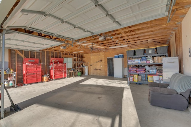 garage featuring a garage door opener, a workshop area, and white fridge