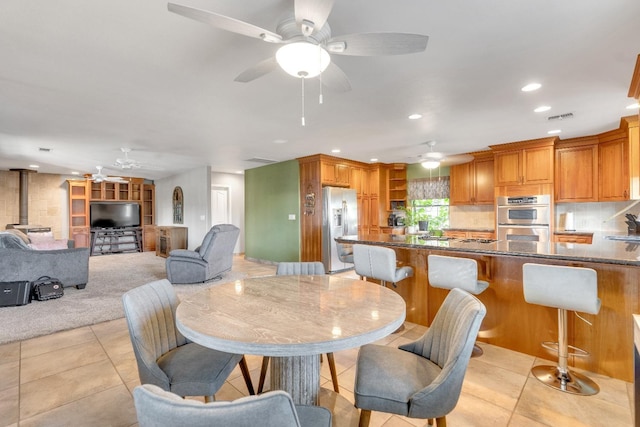 tiled dining room with a wood stove, sink, and ceiling fan