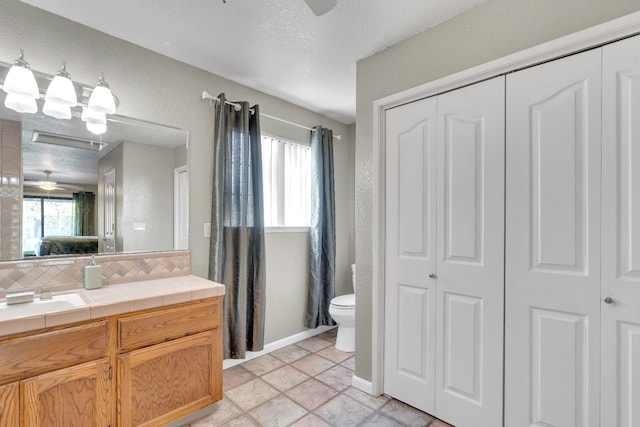 bathroom with backsplash, toilet, a textured ceiling, and ceiling fan