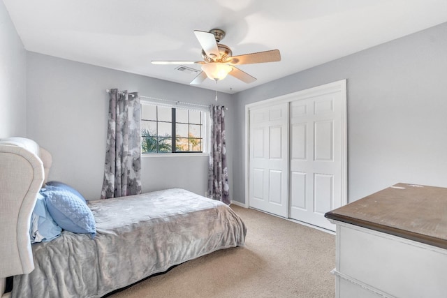 bedroom with ceiling fan, light carpet, and a closet