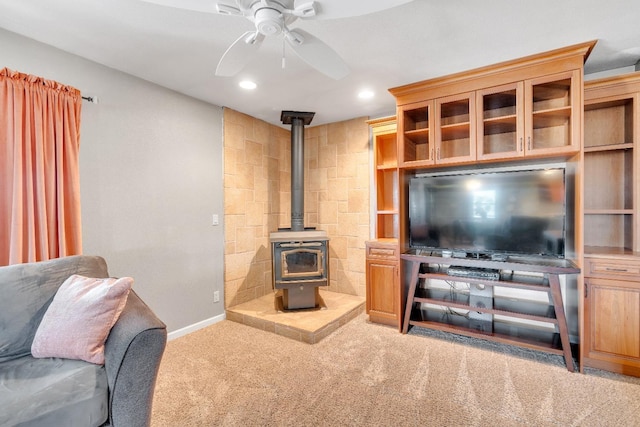 living room featuring ceiling fan, carpet floors, and a wood stove