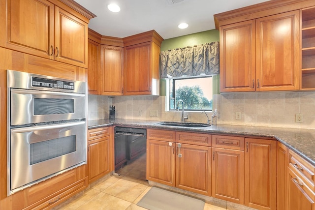 kitchen featuring sink, black dishwasher, tasteful backsplash, dark stone counters, and stainless steel double oven