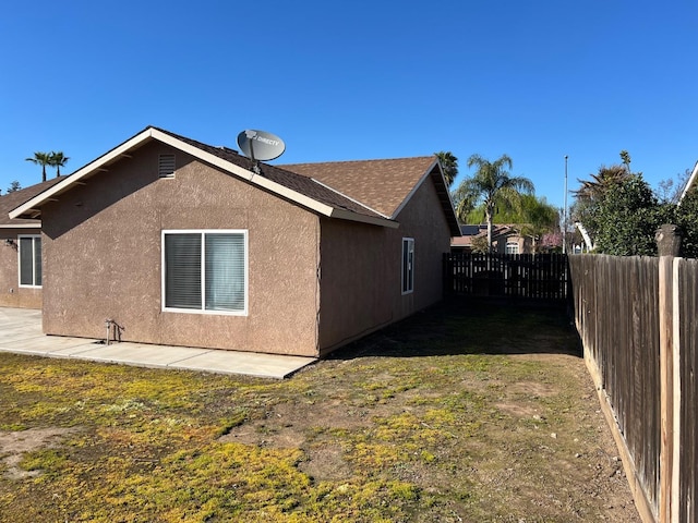 view of side of property with a fenced backyard, a lawn, a patio, and stucco siding