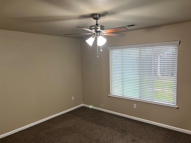 empty room with ceiling fan, dark carpet, and baseboards