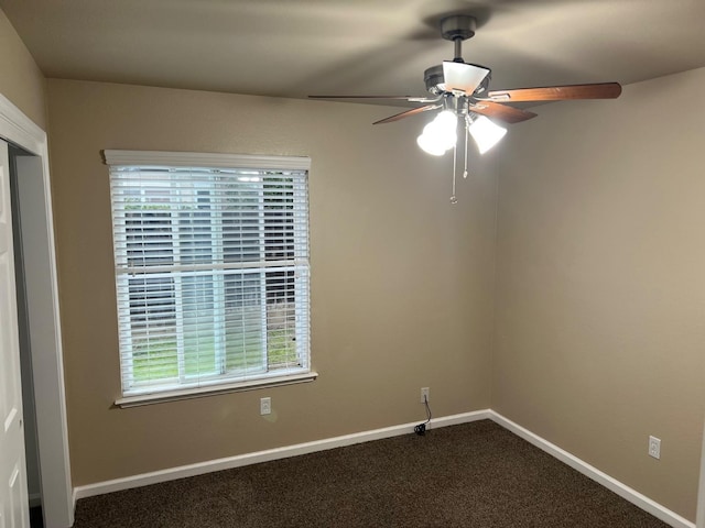 unfurnished room with ceiling fan, dark colored carpet, and baseboards