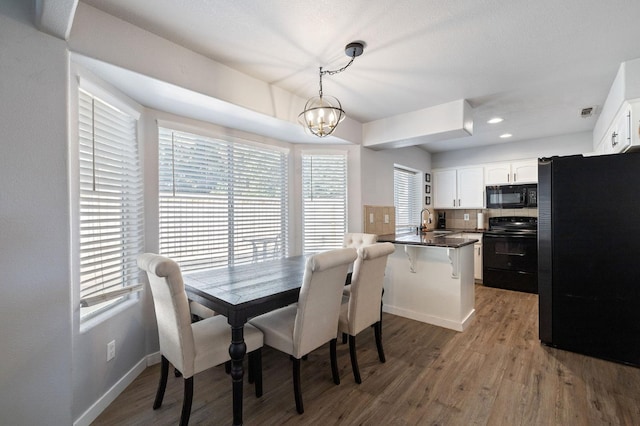 dining area with sink, hardwood / wood-style flooring, and a chandelier