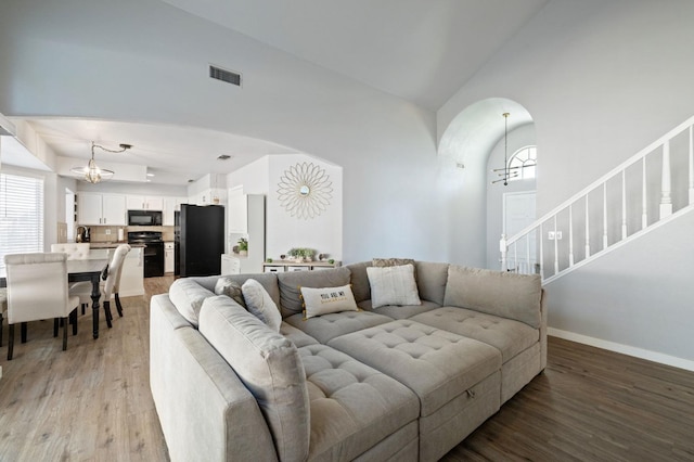 living room with lofted ceiling, sink, a notable chandelier, and light hardwood / wood-style floors