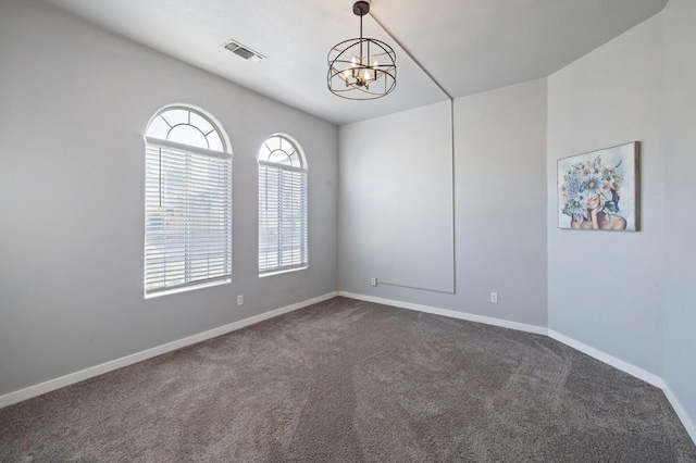 carpeted spare room featuring an inviting chandelier