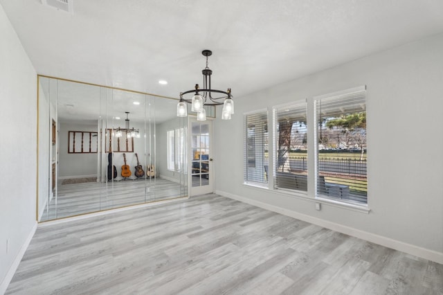 unfurnished dining area featuring a chandelier and light wood-type flooring