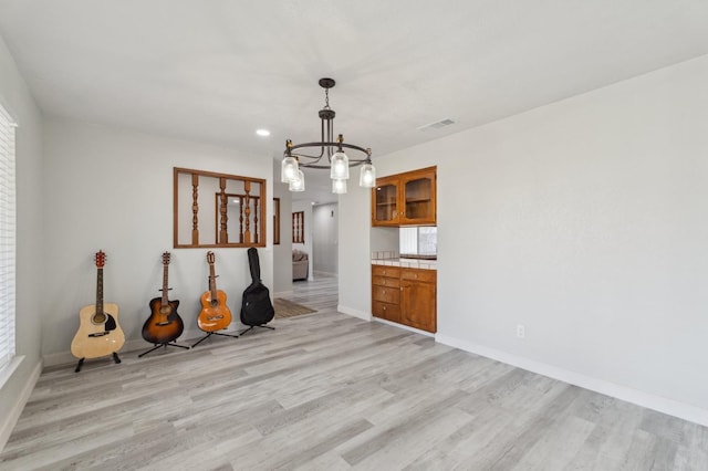 unfurnished dining area featuring light hardwood / wood-style floors and a chandelier