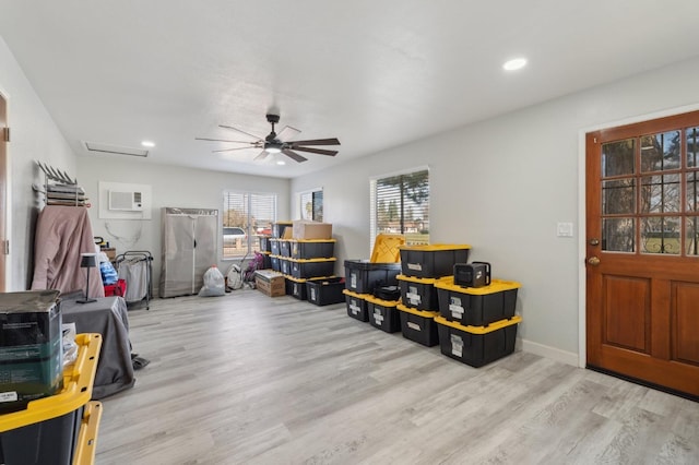 misc room featuring ceiling fan, a wall unit AC, and light wood-type flooring