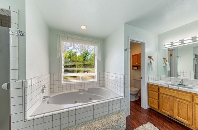 bathroom with vanity, a jetted tub, wood finished floors, and toilet