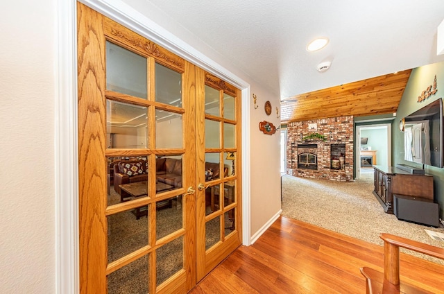 hallway with lofted ceiling, baseboards, wood finished floors, and carpet flooring