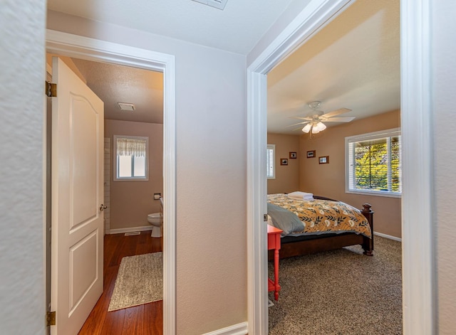 bedroom with a ceiling fan, wood finished floors, connected bathroom, and baseboards