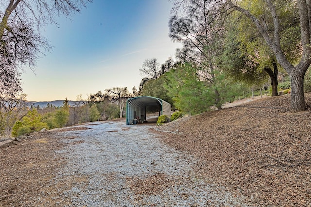 yard at dusk with a detached carport and driveway