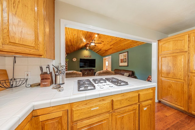 kitchen featuring tile counters, wood ceiling, wood finished floors, a peninsula, and vaulted ceiling