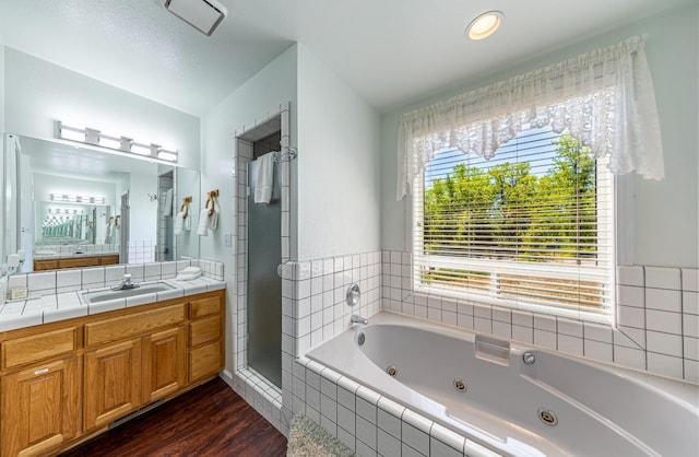 bathroom featuring a stall shower, vanity, a whirlpool tub, and wood finished floors