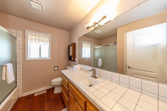 full bath featuring visible vents, toilet, vanity, wood finished floors, and baseboards