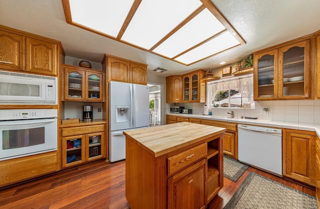 kitchen featuring dark wood-style floors, white appliances, brown cabinetry, and butcher block counters