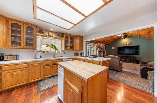 kitchen with lofted ceiling, a peninsula, butcher block countertops, open floor plan, and wood-type flooring