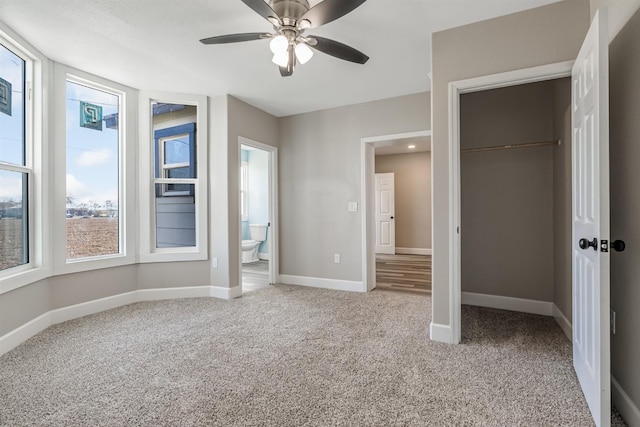 unfurnished bedroom with multiple windows, carpet, ceiling fan, and ensuite bathroom