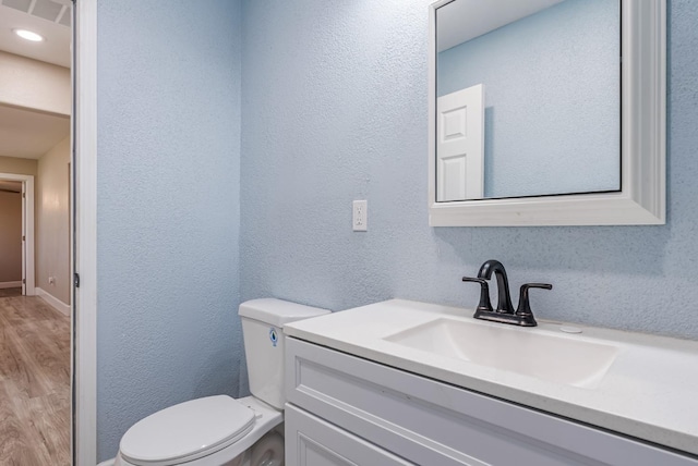 bathroom featuring vanity, wood-type flooring, and toilet