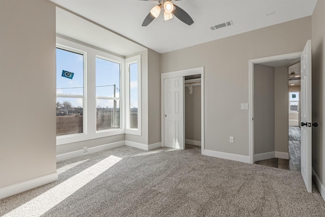 unfurnished bedroom with multiple windows, carpet flooring, ceiling fan, and a closet