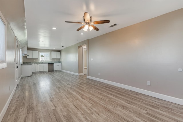 unfurnished living room featuring ceiling fan, sink, and light wood-type flooring