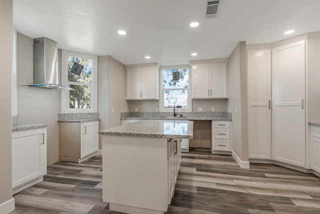 kitchen with white cabinetry, sink, wood-type flooring, and wall chimney range hood