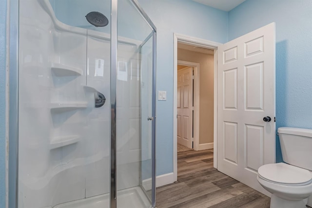 bathroom with hardwood / wood-style flooring, toilet, and walk in shower