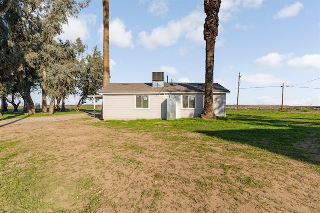 rear view of property featuring cooling unit and a yard