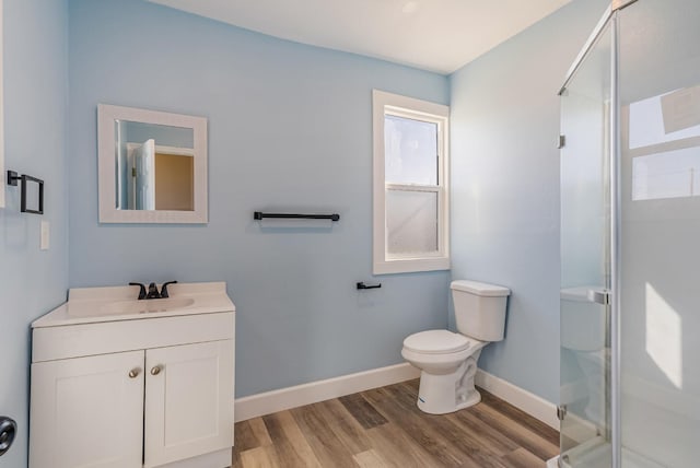 bathroom featuring vanity, toilet, a shower with shower door, and wood-type flooring