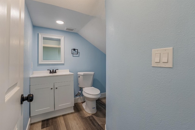 bathroom featuring wood-type flooring, toilet, vaulted ceiling, and vanity