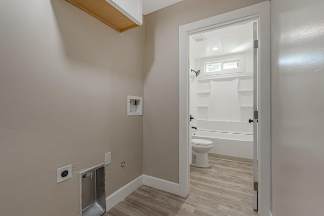 laundry area featuring electric dryer hookup, hookup for a washing machine, and light hardwood / wood-style flooring