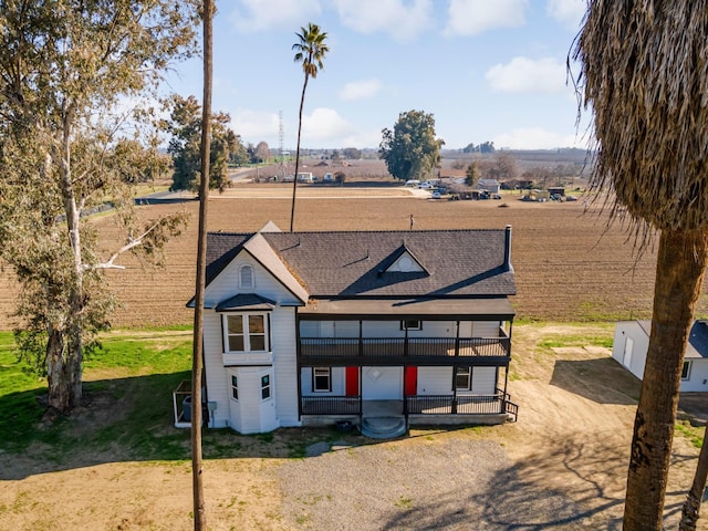 view of front of house with a balcony and a rural view