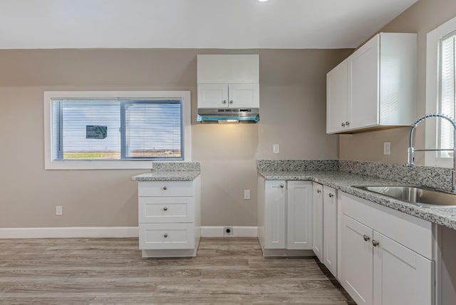 kitchen with white cabinetry, light stone countertops, sink, and light wood-type flooring