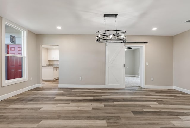 unfurnished dining area featuring a barn door and light wood-type flooring