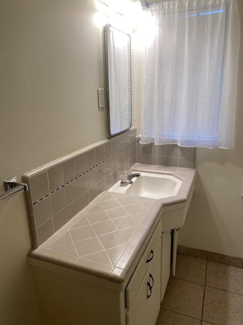 bathroom featuring vanity, baseboards, backsplash, and tile patterned floors