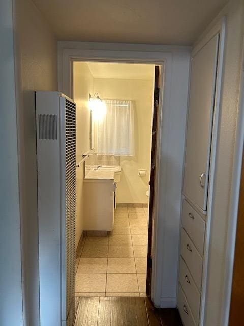 bathroom with baseboards, a heating unit, vanity, and tile patterned floors