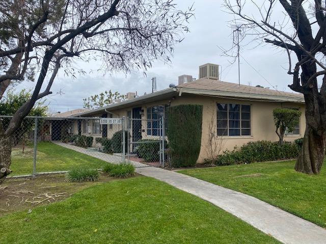 view of front of house featuring a gate, fence, a front lawn, and stucco siding