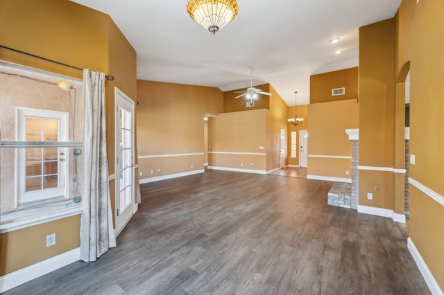 empty room with ceiling fan with notable chandelier, vaulted ceiling, and dark hardwood / wood-style floors