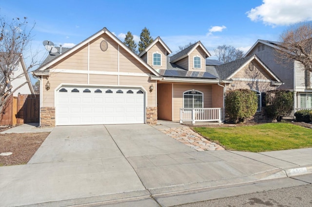 view of front of home with a garage, a front lawn, solar panels, and a porch