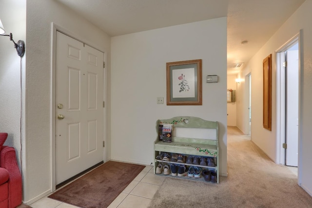 foyer entrance featuring light tile patterned floors and light carpet