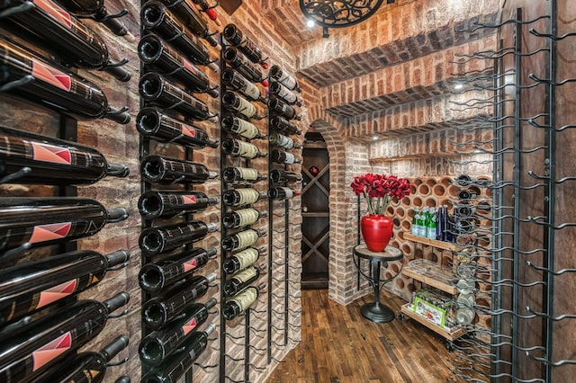 wine area with brick ceiling and dark hardwood / wood-style floors