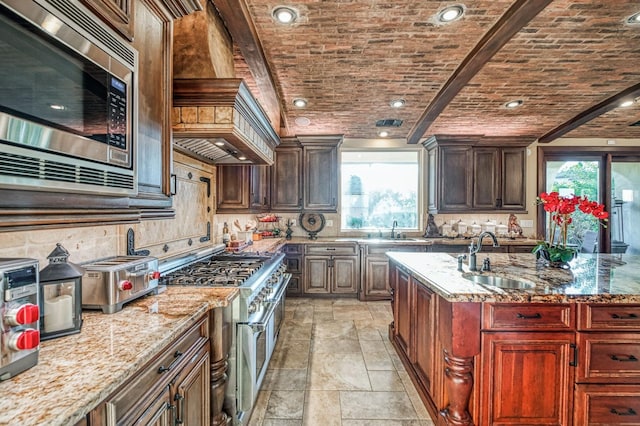 kitchen with stainless steel appliances, brick ceiling, sink, and light stone counters