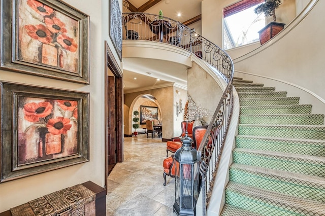 staircase with crown molding and a high ceiling