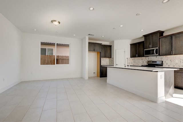 661 Lucas Ave S, Madera, CA 93636 - kitchen with stainless steel appliances, backsplash, a sink, a kitchen island with sink, and dark brown cabinets